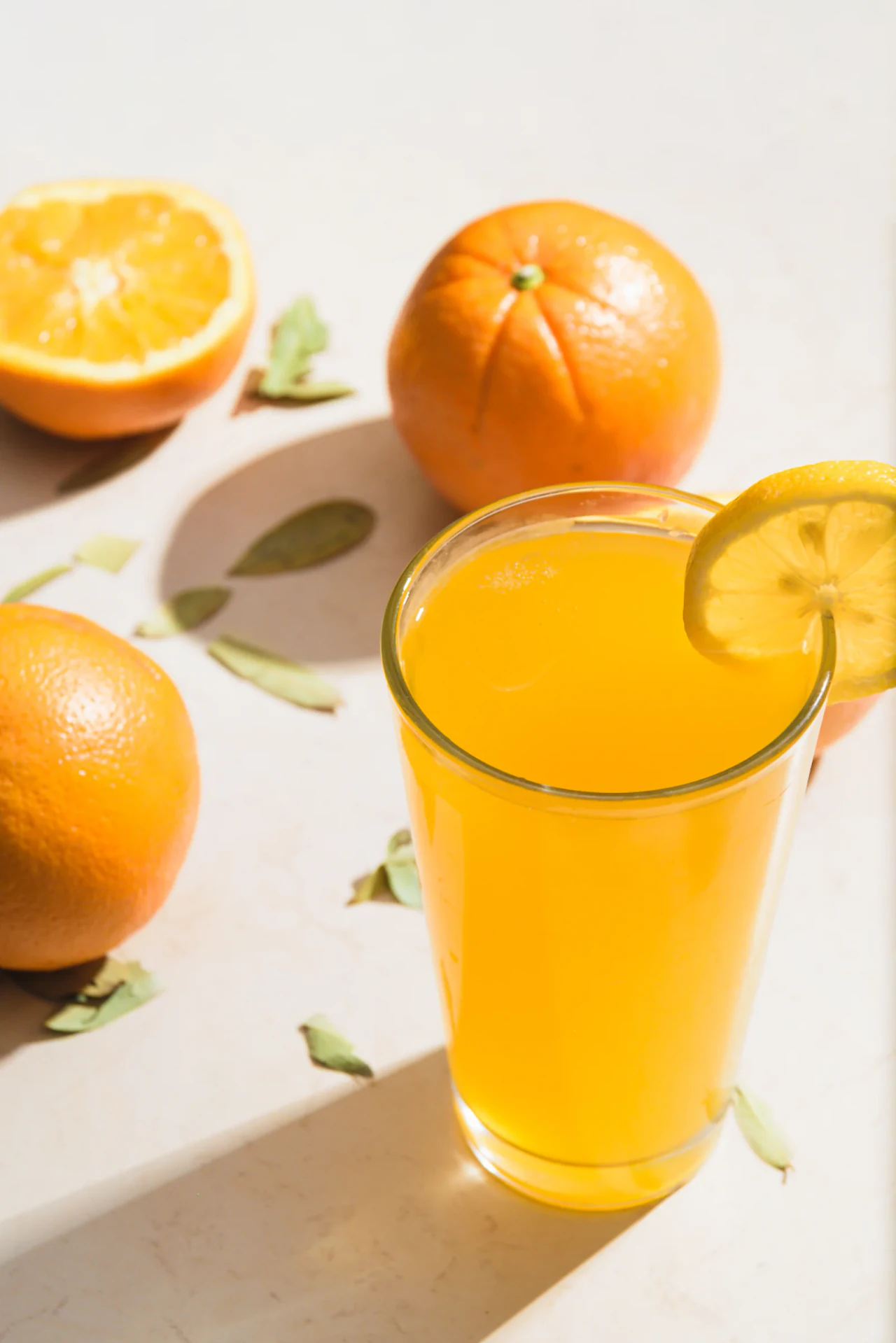 Vaso alto de jugo de naranja natural con naranjas partidas al lado