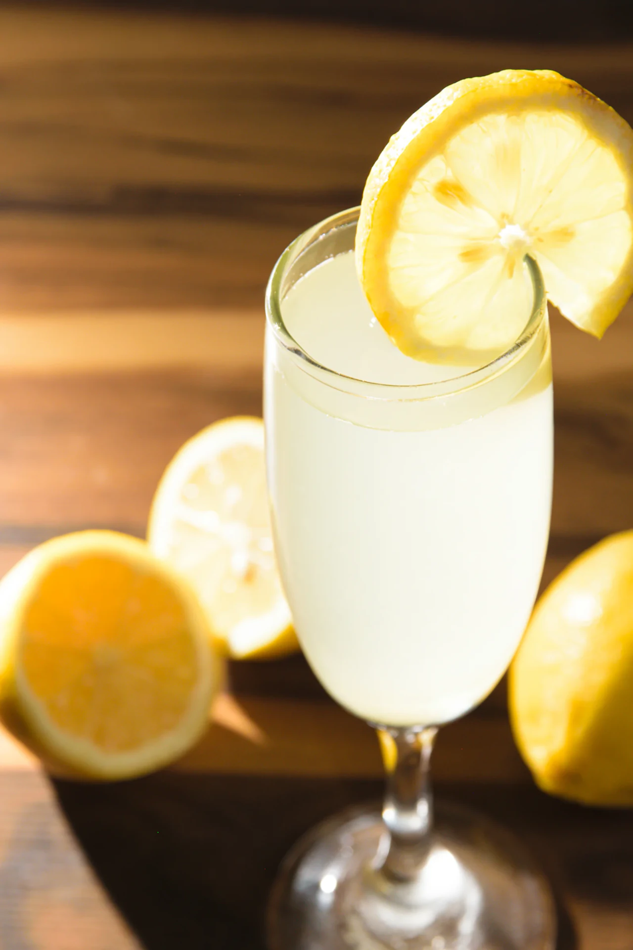 Copa de limonada con rodajas de limón e iluminación cálida sobre madera