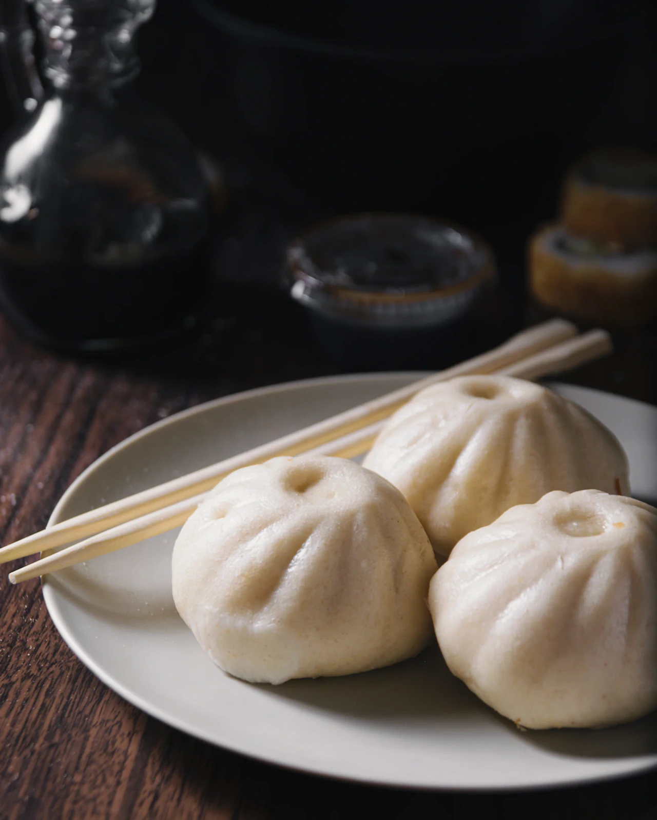 Baos al vapor servidos en plato blanco con palillos de madera